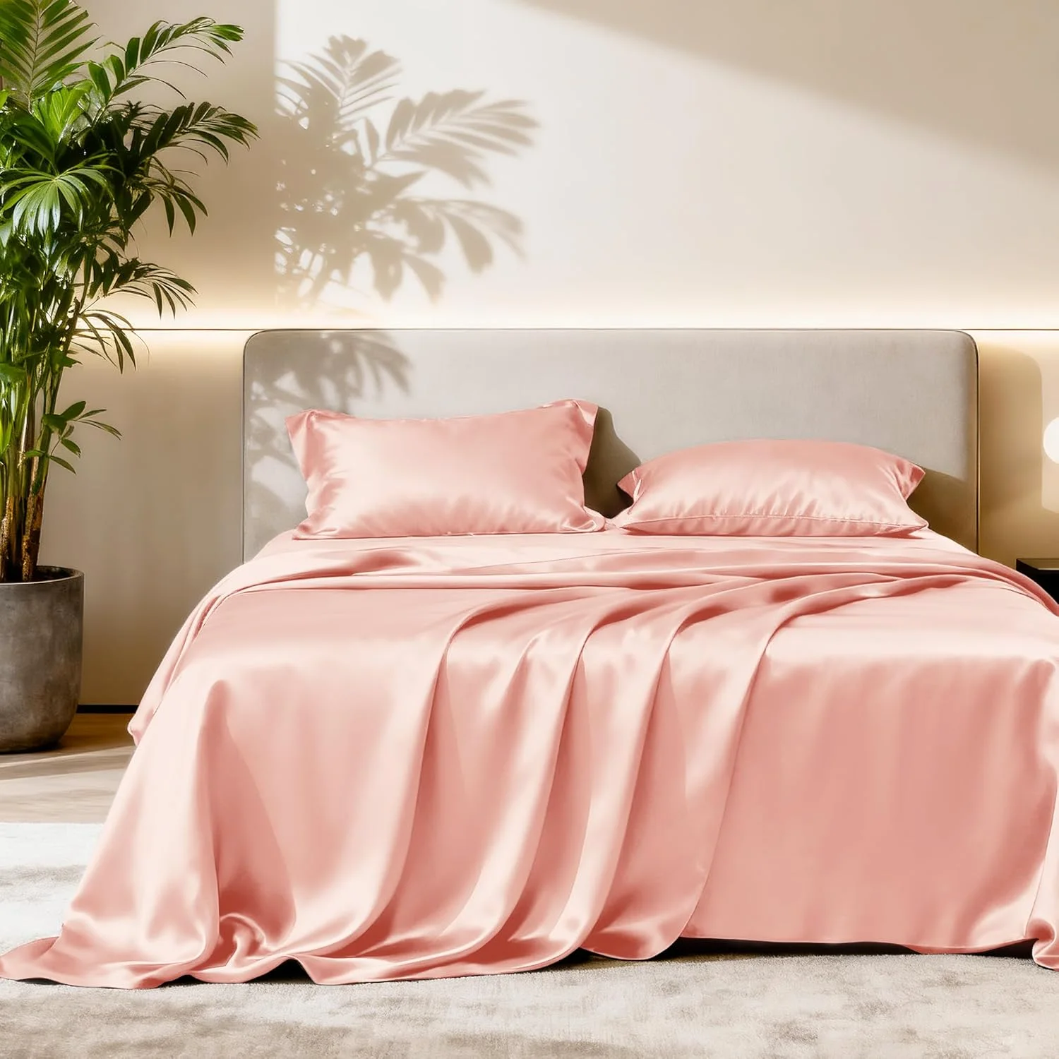 Pink satin sheet set draped over a queen bed